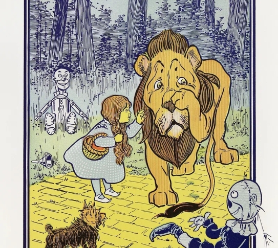 An illustration from "The Wonderful Wizard of Oz". Dorothy is trying to comfort the Cowardly Lion as the Scarecrow, the Tin Man, and her dog Toto watch.