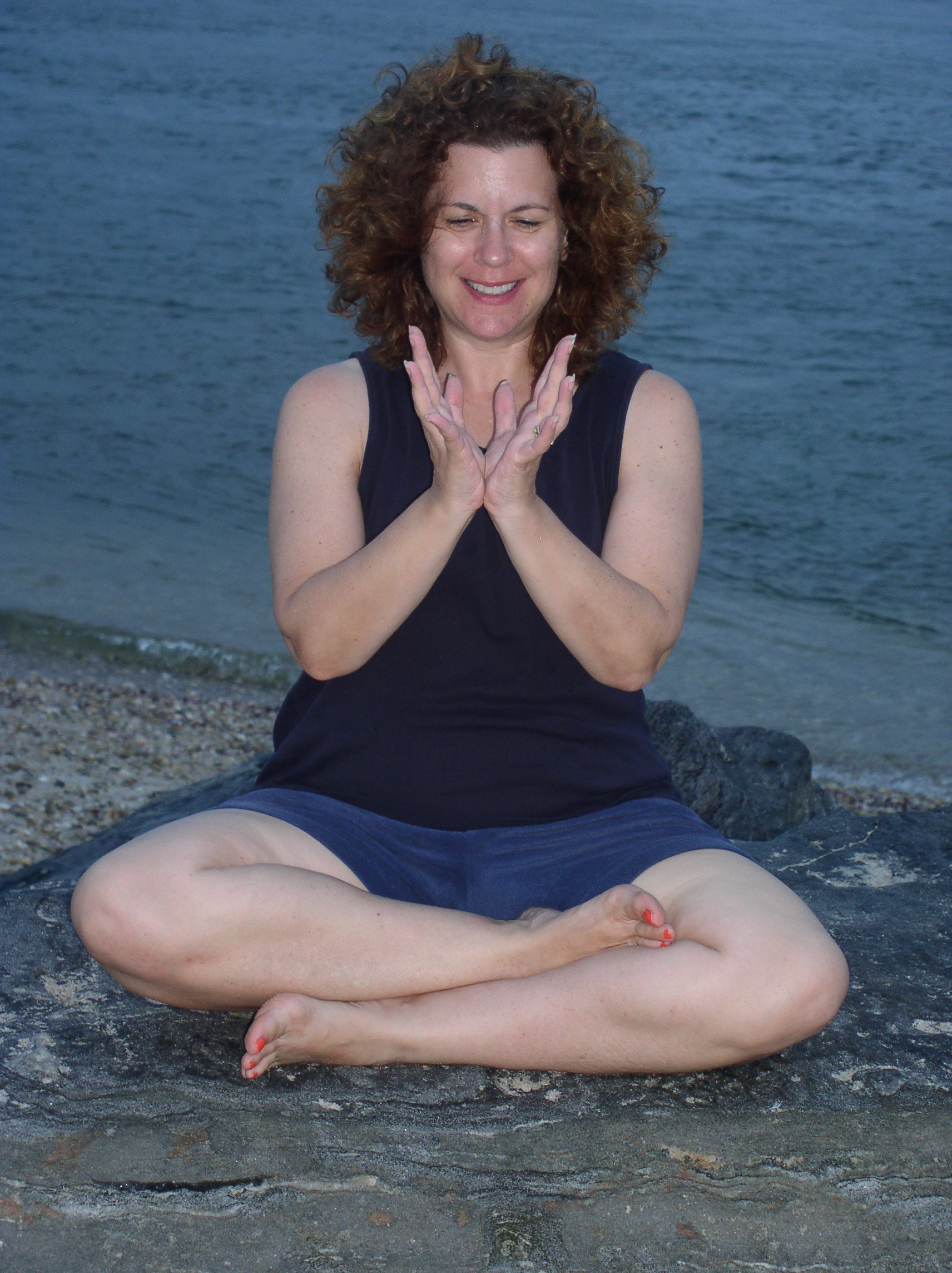 Image of Louise Fecher in a yoga pose by the ocean