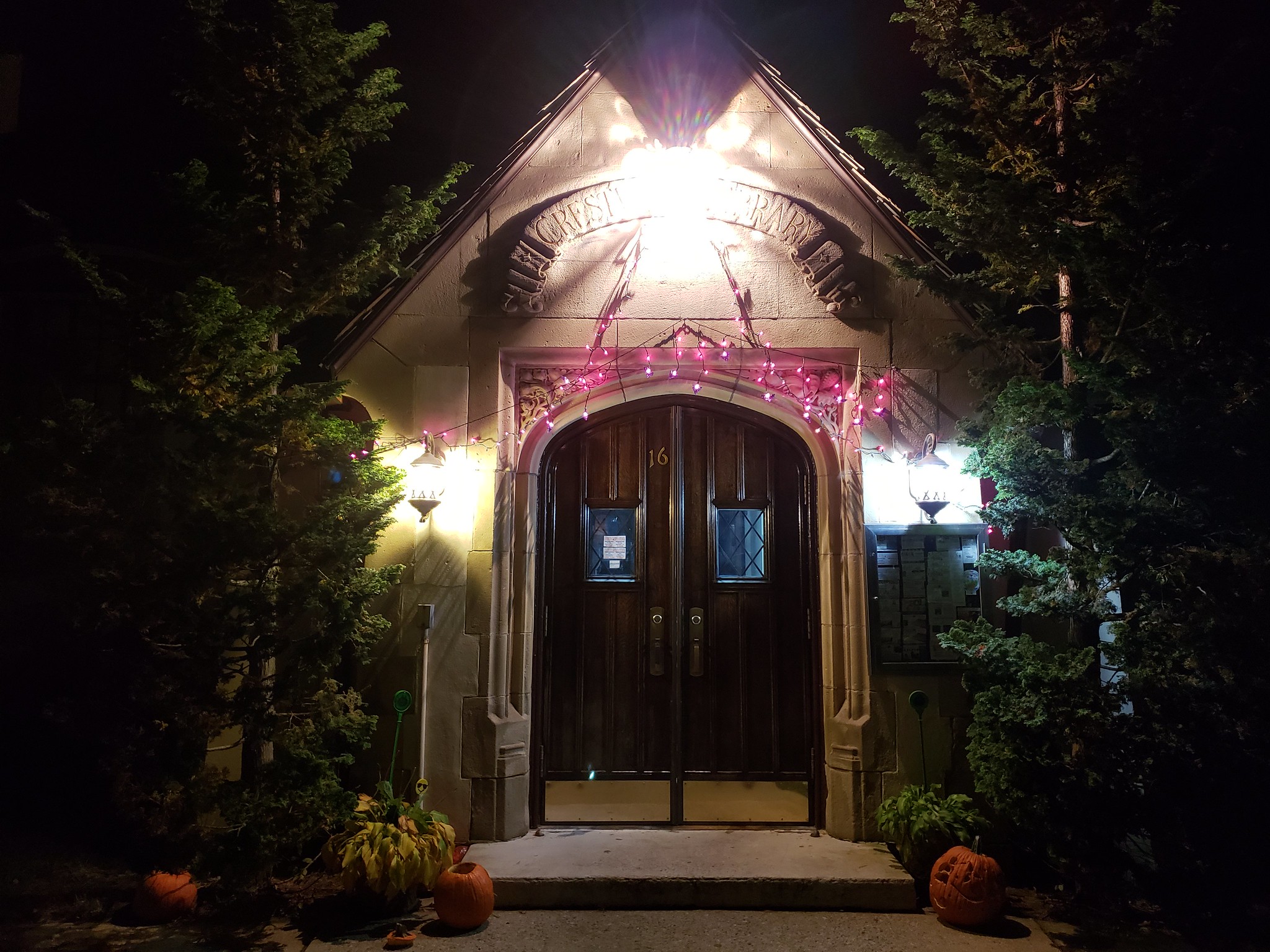 Photo of Crestwood Library in the dark with pumpkins and purple lights