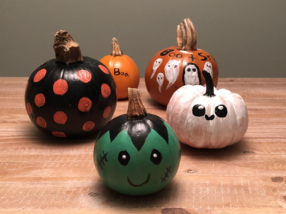 5 small pumpkins with halloween decorations painted on them