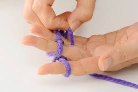 photography of two hands with yarn finger knitting