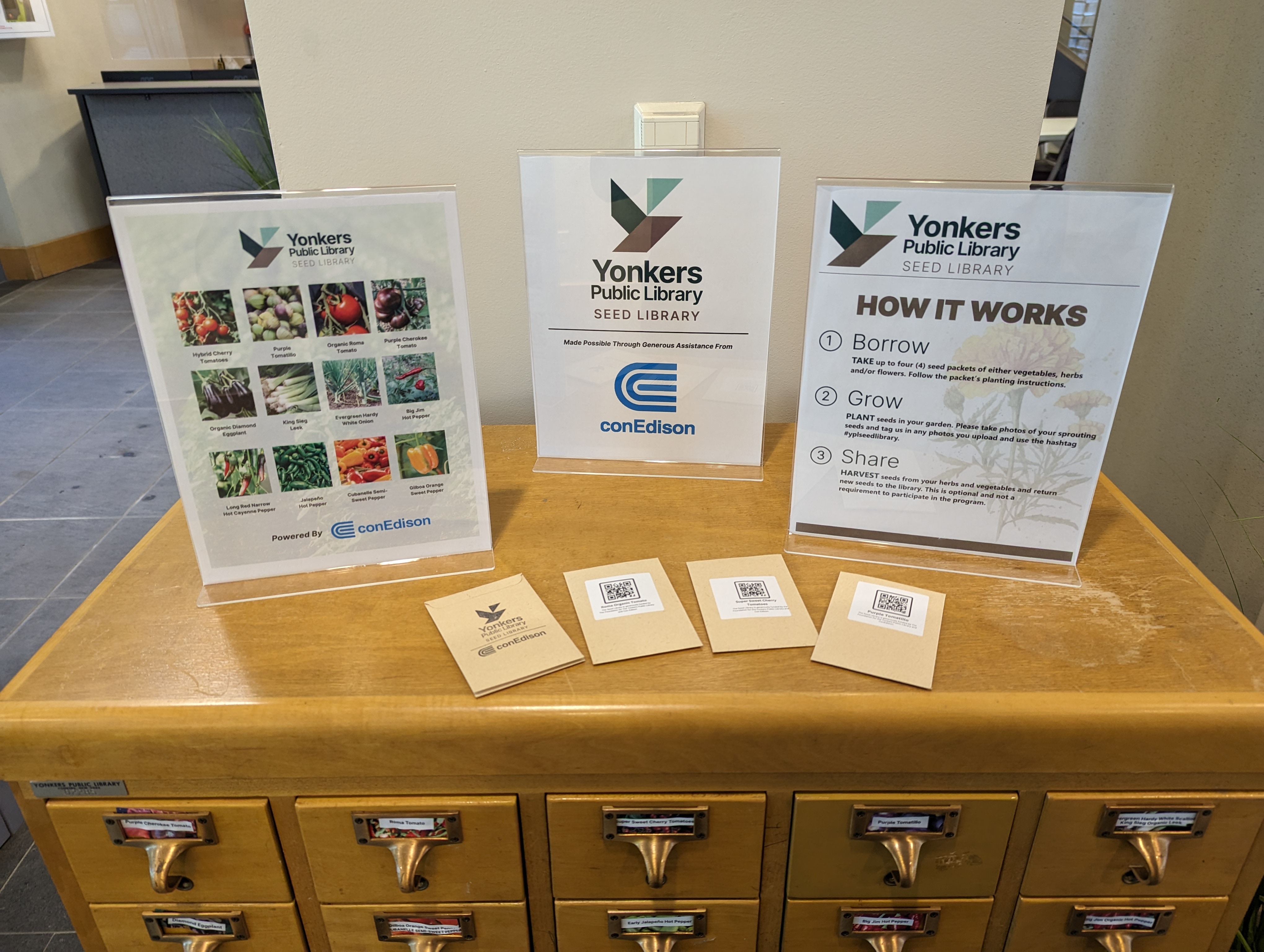 Photo of a card catalog with seed packets and a sign reading "YPL Seed Library"