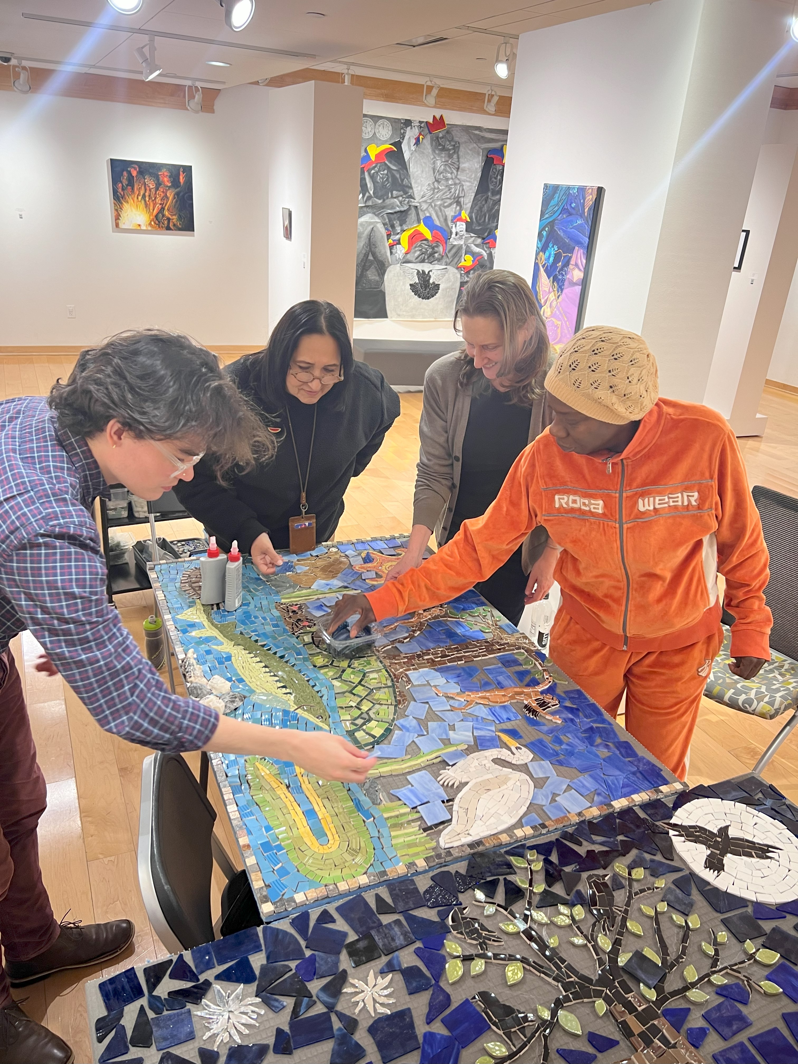 Haifa Bint-Kadi and community memberscommunity members Deborah Diamond, Christoph Sawyer, and Linda Winters work on the mosaic in the Art Gallery