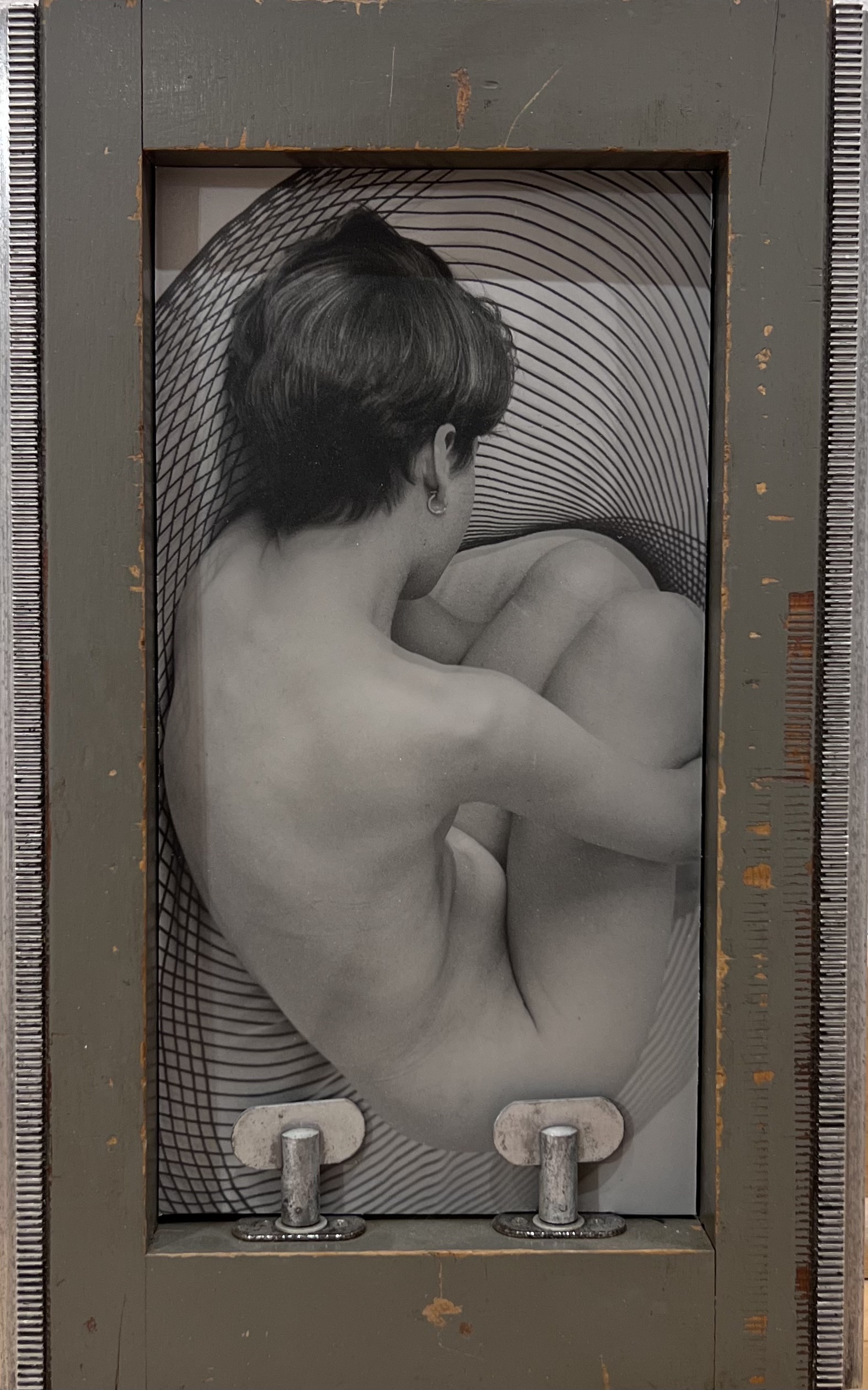 Black and white photograph from a bird's eye view of a nude body framed by wood