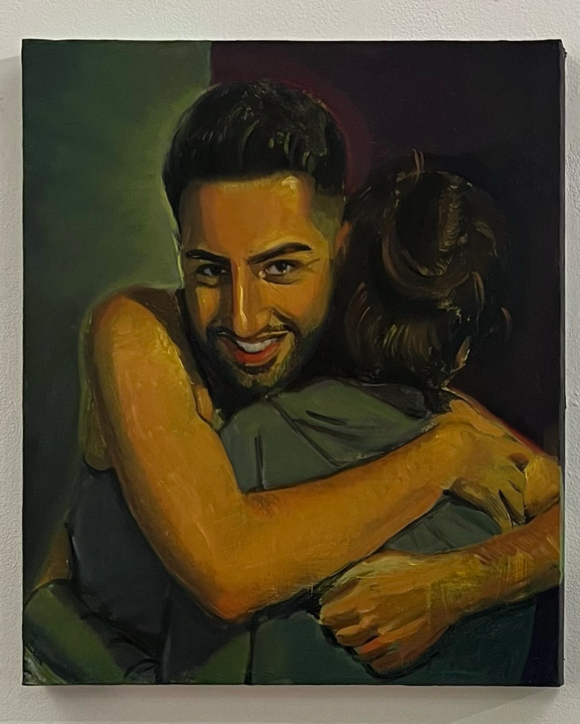 Portrait of someone smiling and facing the audience while hugging another person whose face is hidden