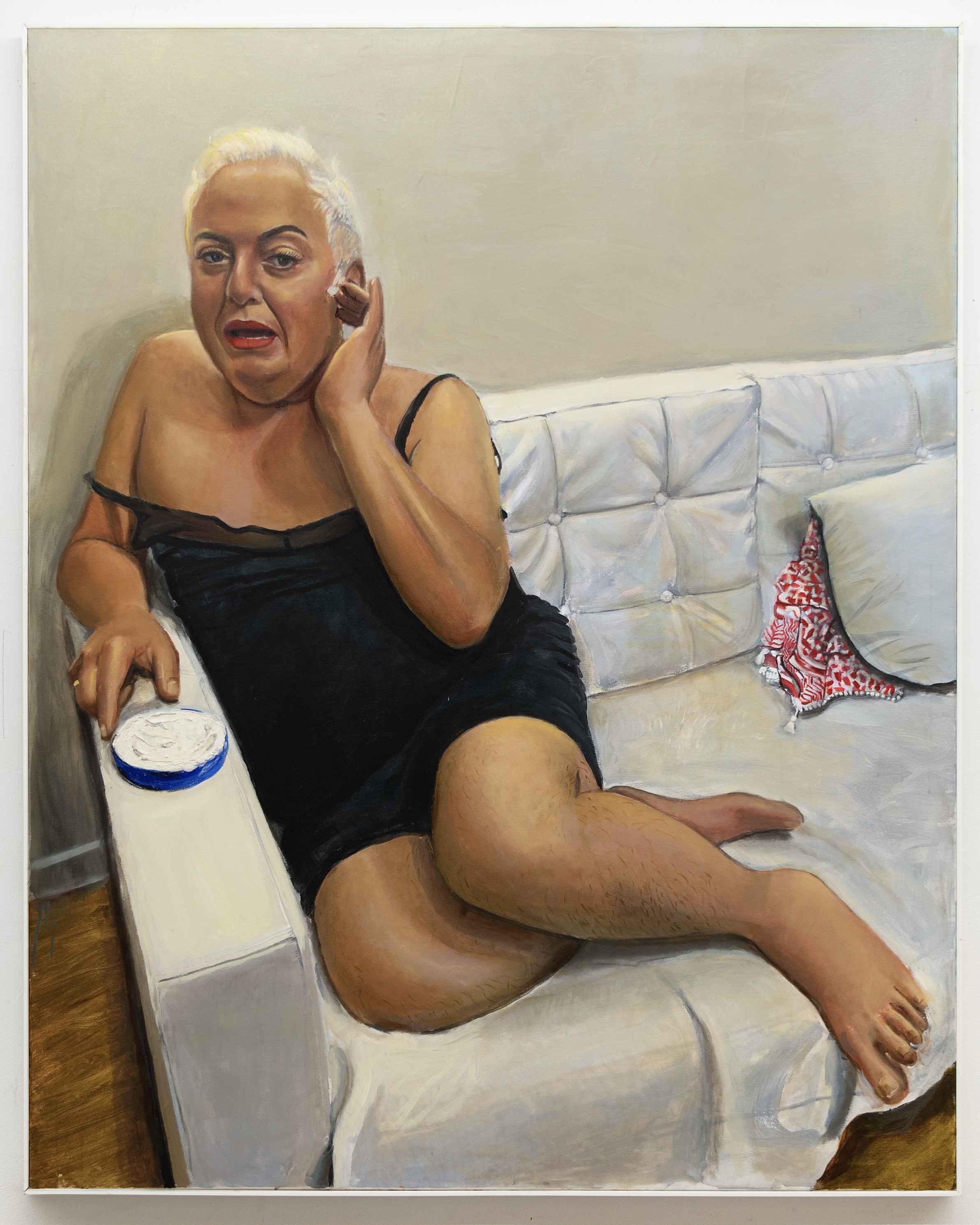 Portrait of someone lounging on a white couch in a loose black slip dress, in the middle of saying something