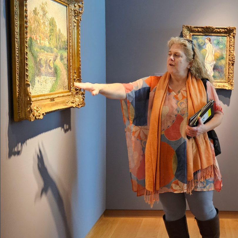 Val Franco pointing out details in a painting at the Bruce Museum.