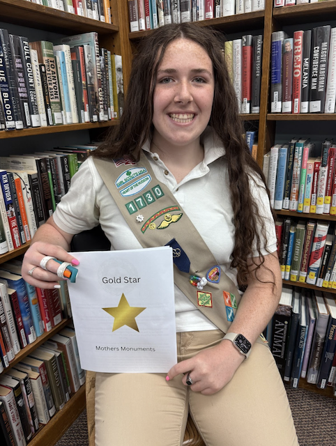 Girl Scout Alana holding up her project about the Gold Star Mothers monuments in Westchester County.