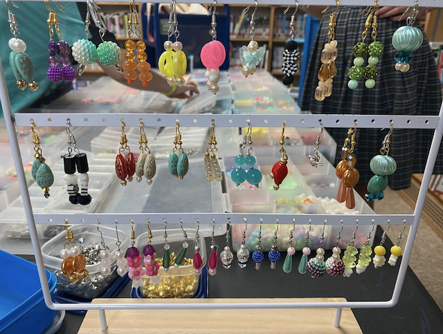 Pairs of earrings for Crafts with a Cause on a three-tiered display rack.