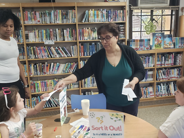 Sally Pinto working with a young patron at the financial literacy festival.