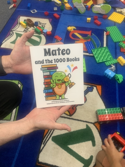 Hand holding a book with a turtle titled "Mateo and the 1000 Books"