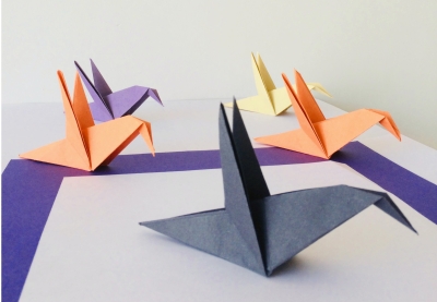 Five origami birds made of different colors of paper are displayed on a table.