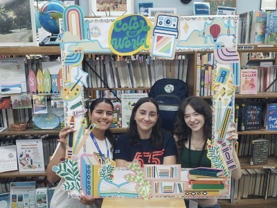 A photo of three Crestwood Volunteens in front of a bookcase using a Summer Reading Color Our World photo frame.