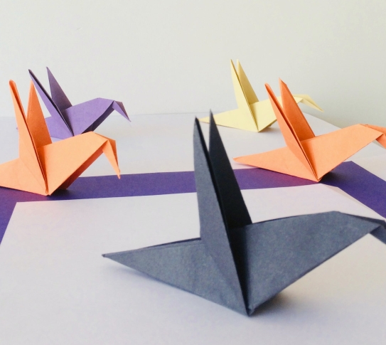Five origami birds made of different colors of paper are displayed on a table.