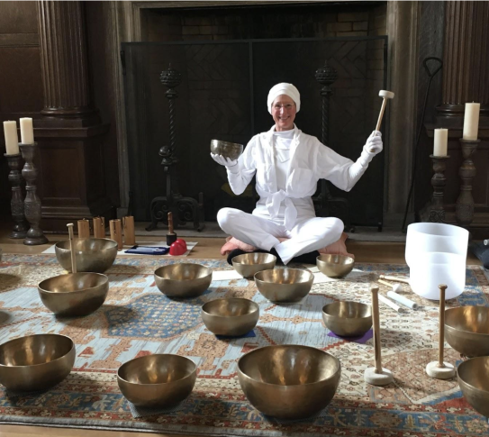 Michelle Clifton with her Tibetan Sound Bowls laid out on the ground in front of her.