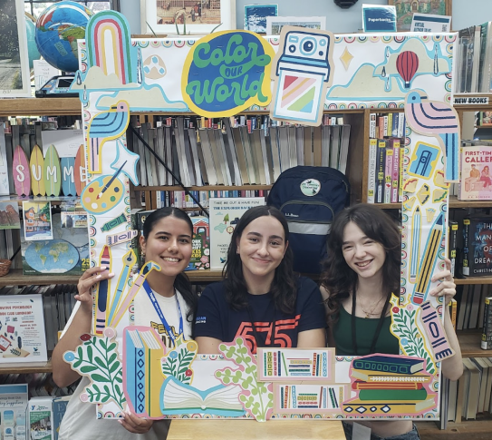 A photo of three Crestwood Volunteens in front of a bookcase using a Summer Reading Color Our World photo frame.