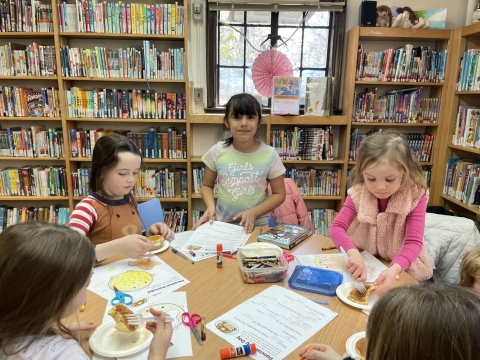 Image of children eating pancakes and making crafts.