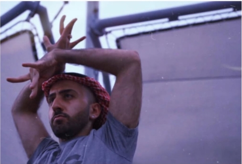 Artist RIDIKKULUZ in the middle of voguing with their hands splayed and held above their head