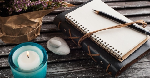 unlit candle journal and pen on a table
