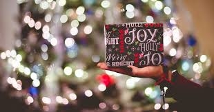 image of a hand holding a gift in front of holiday lights
