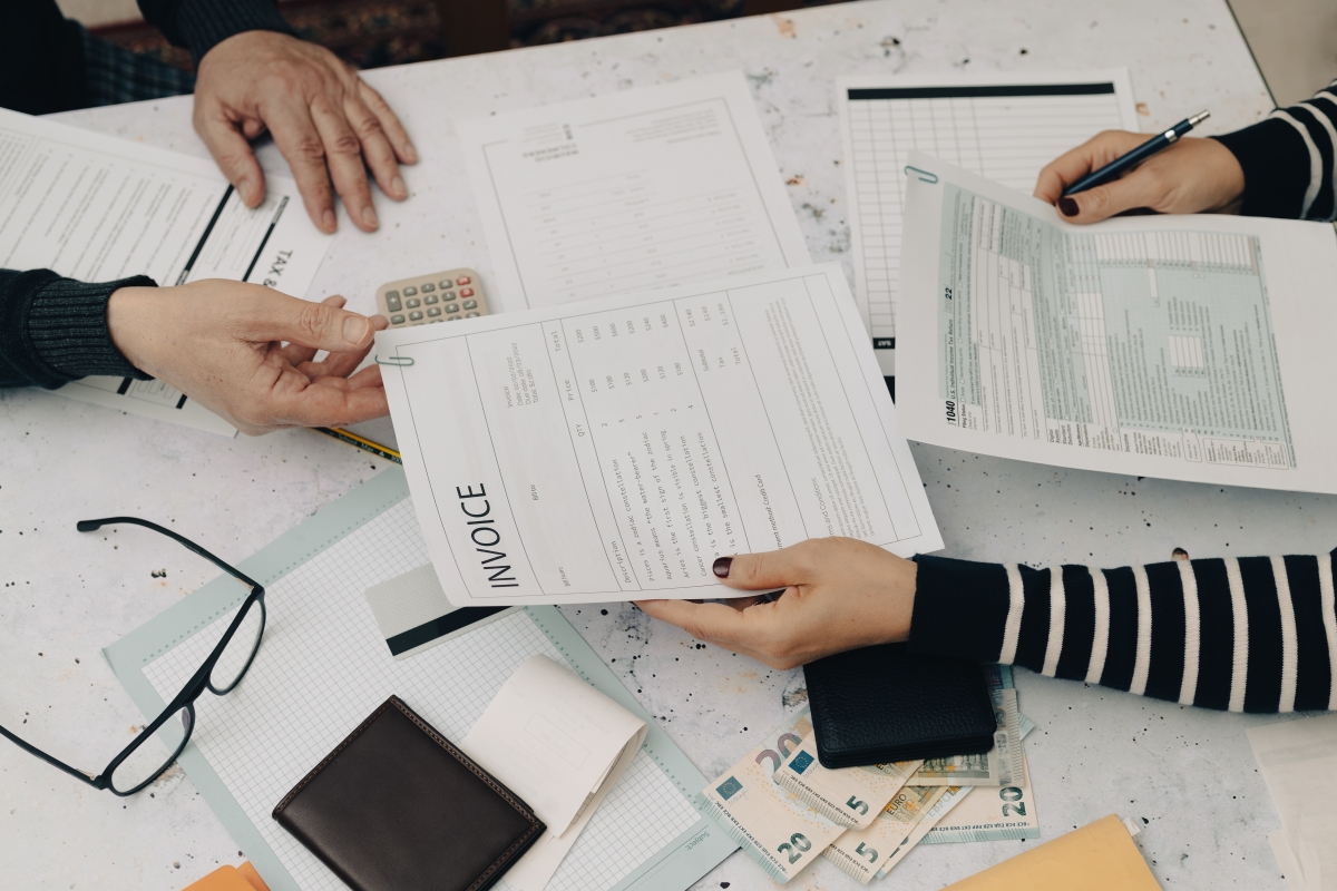 Two people with table filled with tax forms and calculator 