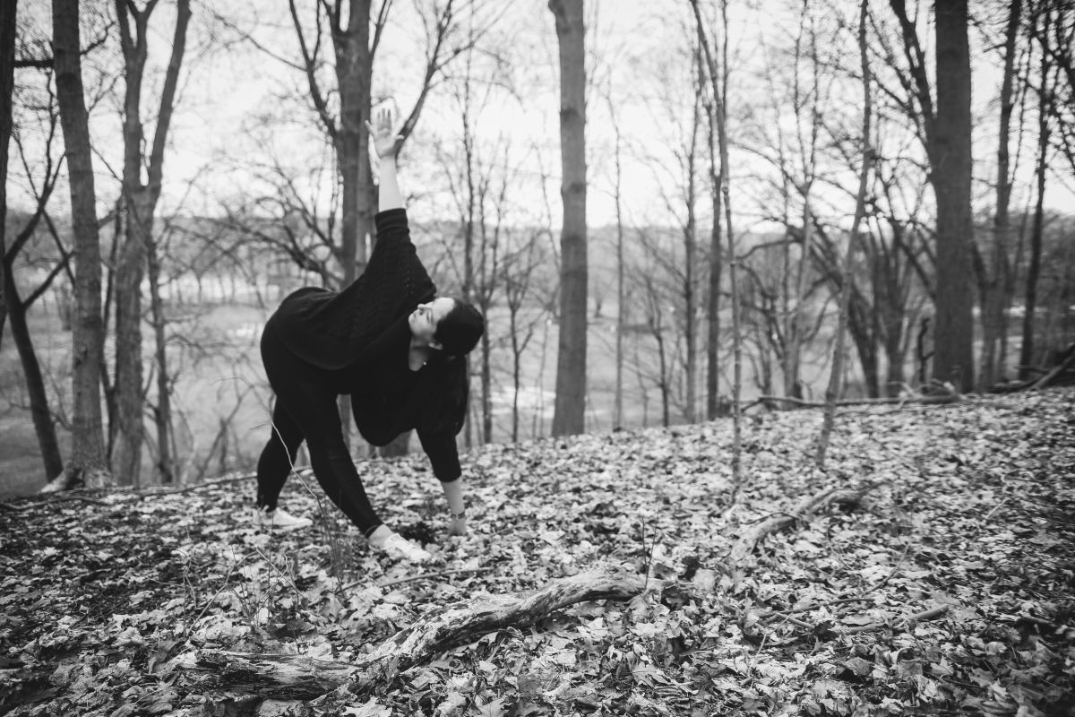 Shannon Reilly bent over in a yoga pose in the woods