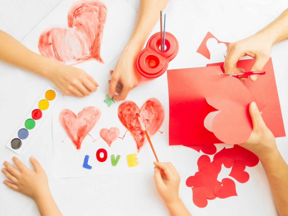 hands cutting out hearts and painting valentines