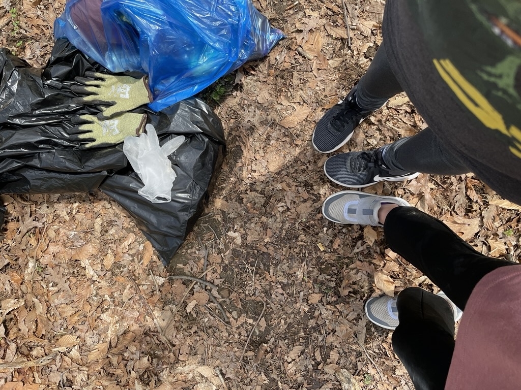 Image of bags, gloves, and volunteers sneakered feet on the forest floor