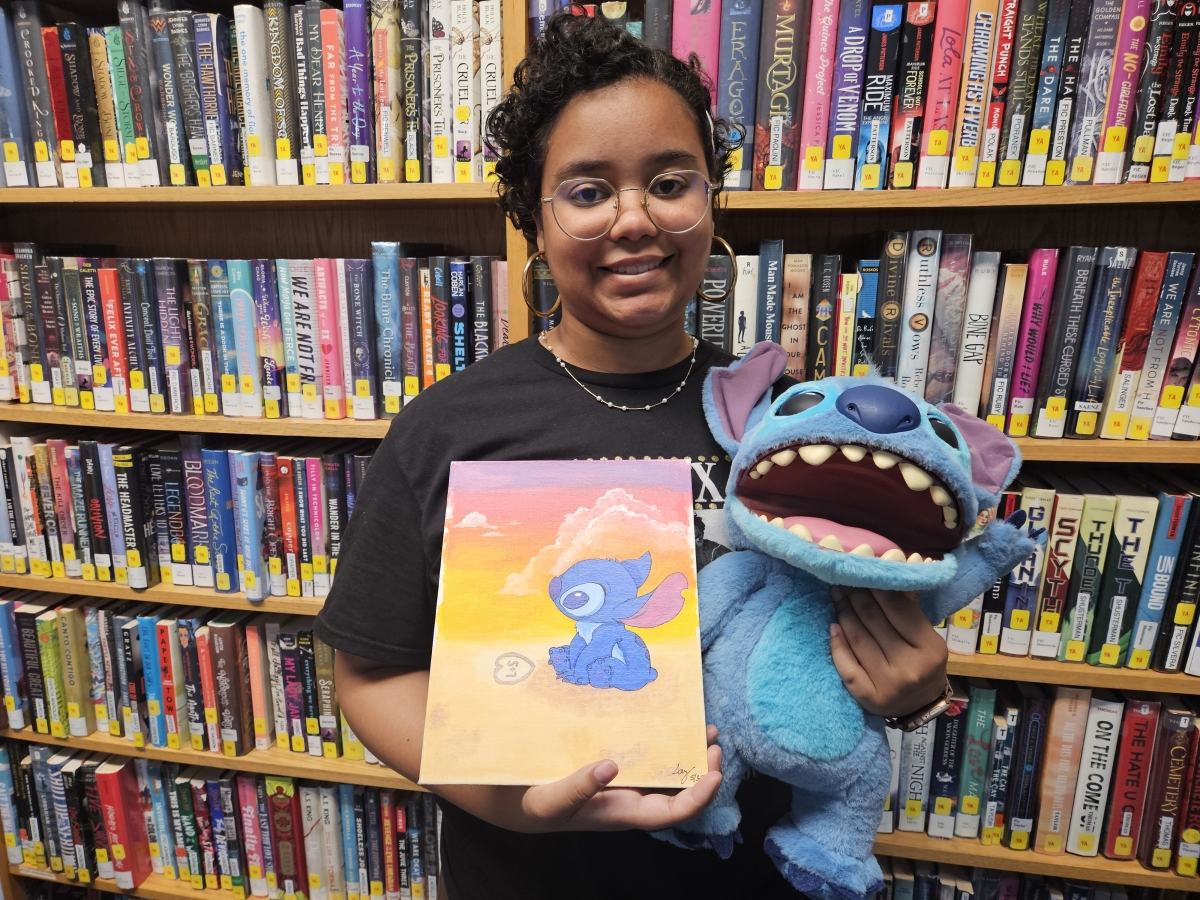 Say Marte posing with Stitch and a painting of Stitch.