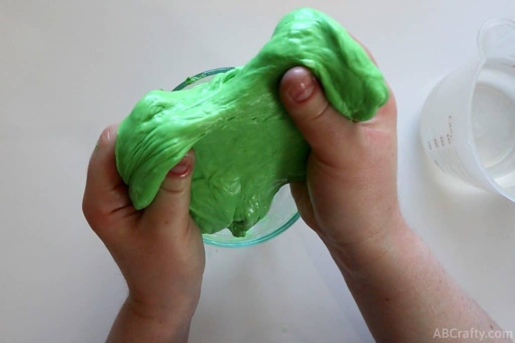 two hands holding lump of green slime
