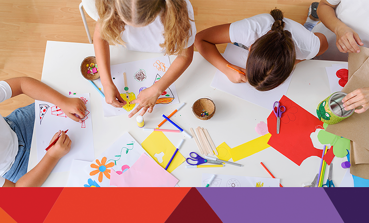 kids at a table with scissors paper glue crafting 