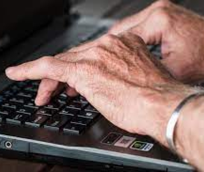 Senior hands over a black laptop 