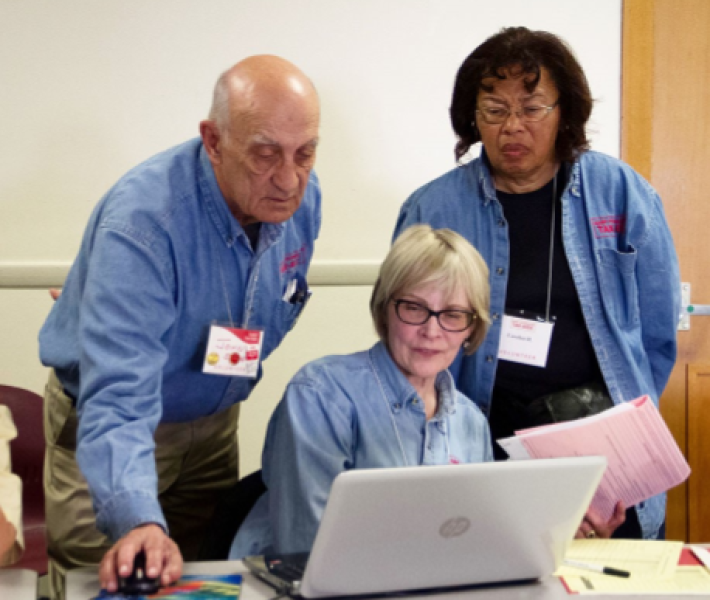 AARP volunteers helping someone at the computer