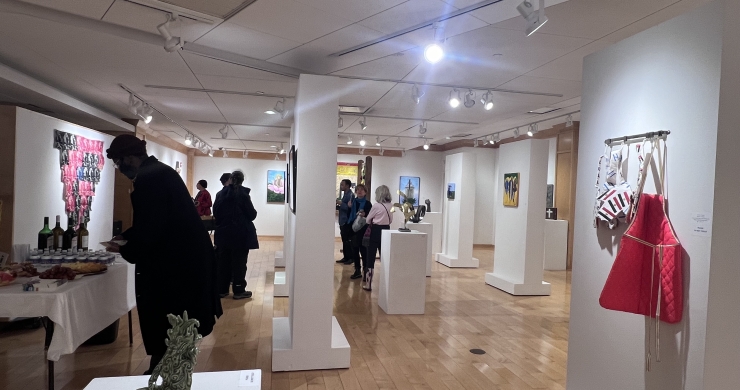 Patrons enjoying snacks and the artwork at the Bridging Chasms opening reception. Featured works: "Serenity" by Shaina Aiyana-Dunn, "Kitchen Cabinet" by Susan C. Dessel, "New Hierarchy" by V Tineo and "Mark I (aka Collision)" by Damon Hamm